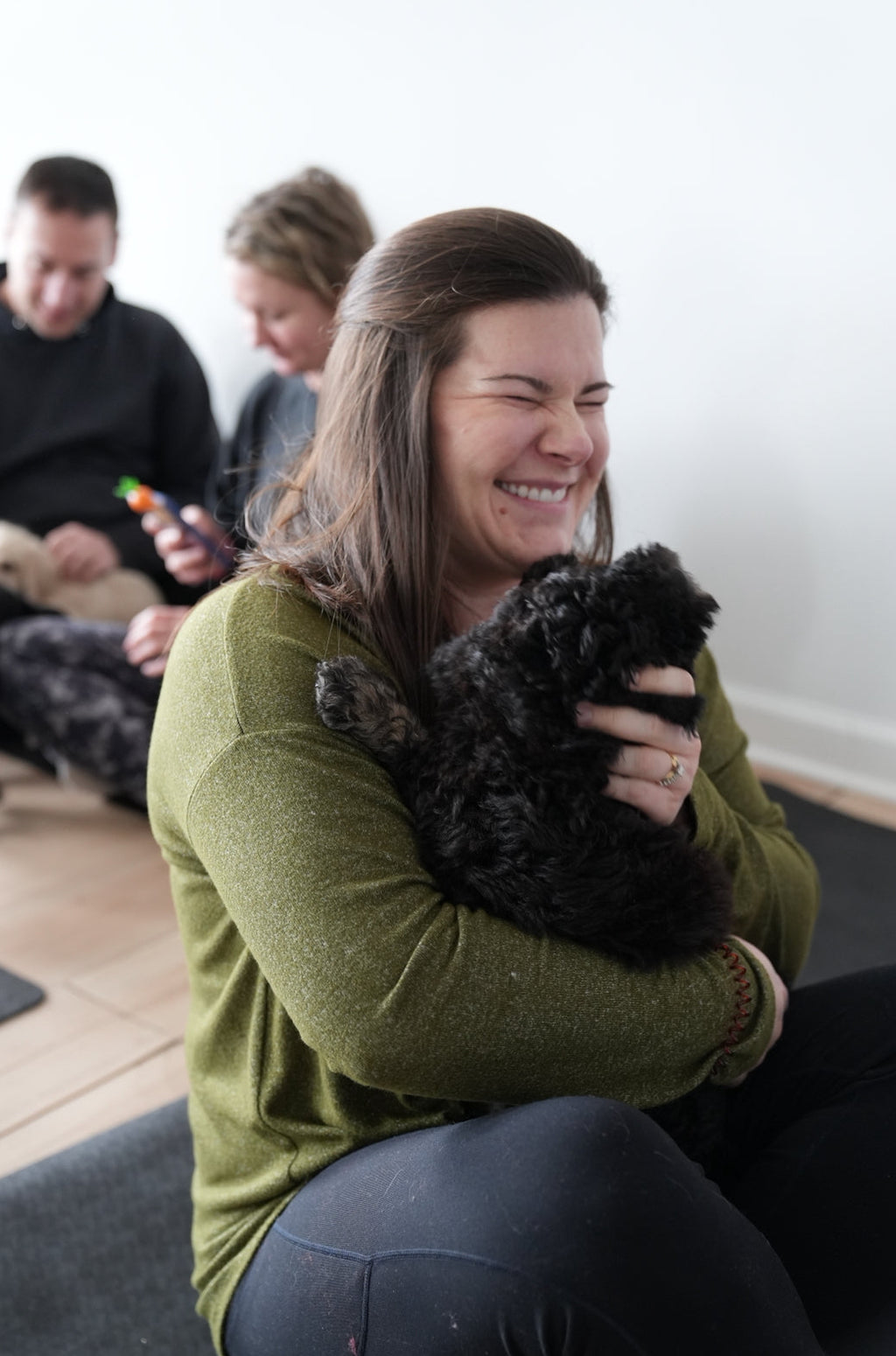 Woman holding a black dog during puppy yoga in chicago suburbs with other people and pets.